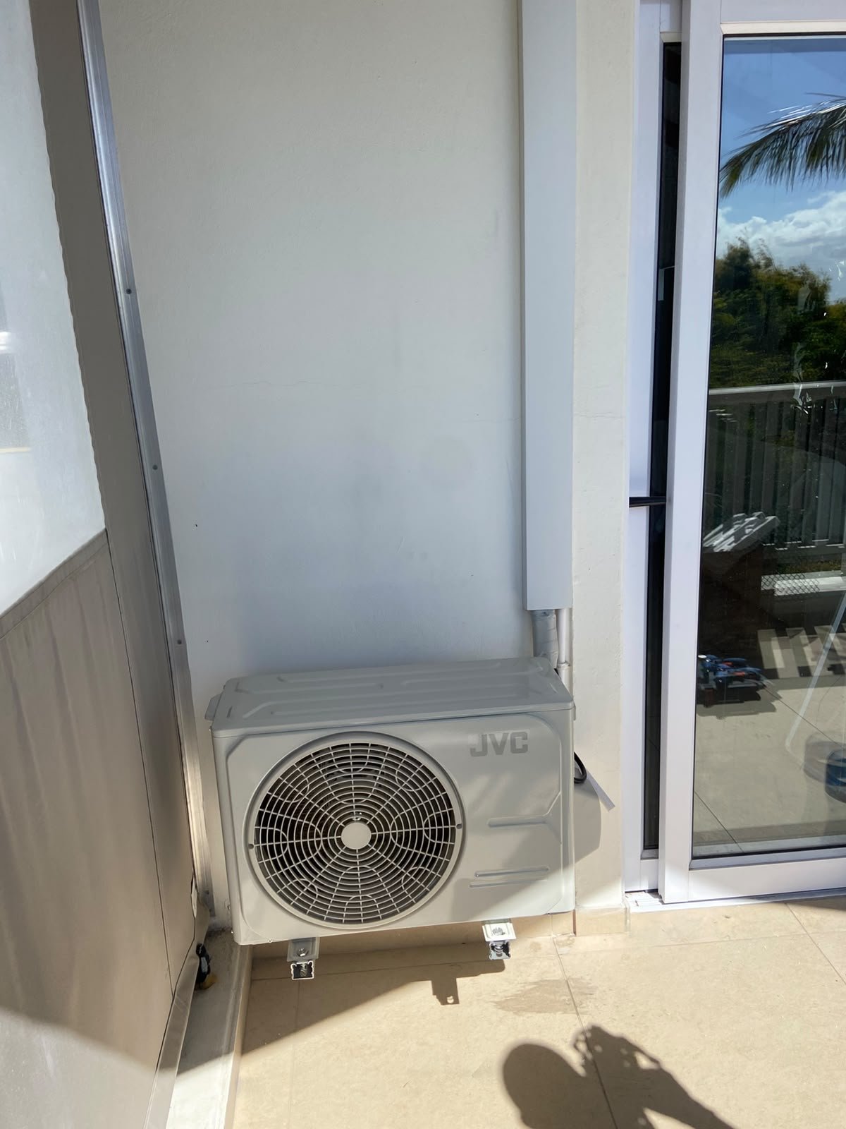 Aircon outdoor unit on a balcony with white trunking, installed by Mount-IT